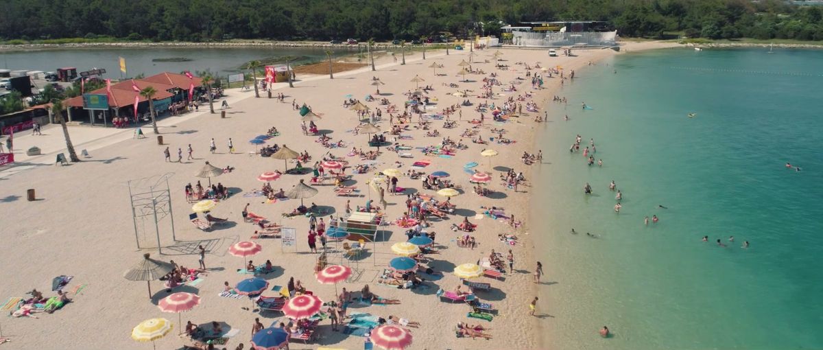 Zrće Beach from above: pebble beach, umbrellas and turquoise sea